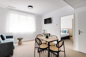 Une chambre moderne équipée d’une table à manger, de chaises, d’un canapé, d’une télévision et d’un lit.