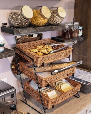 A buffet setup with wicker baskets containing bread, pastries, and jars of condiments. - Montempô Lille Gares (Lille)