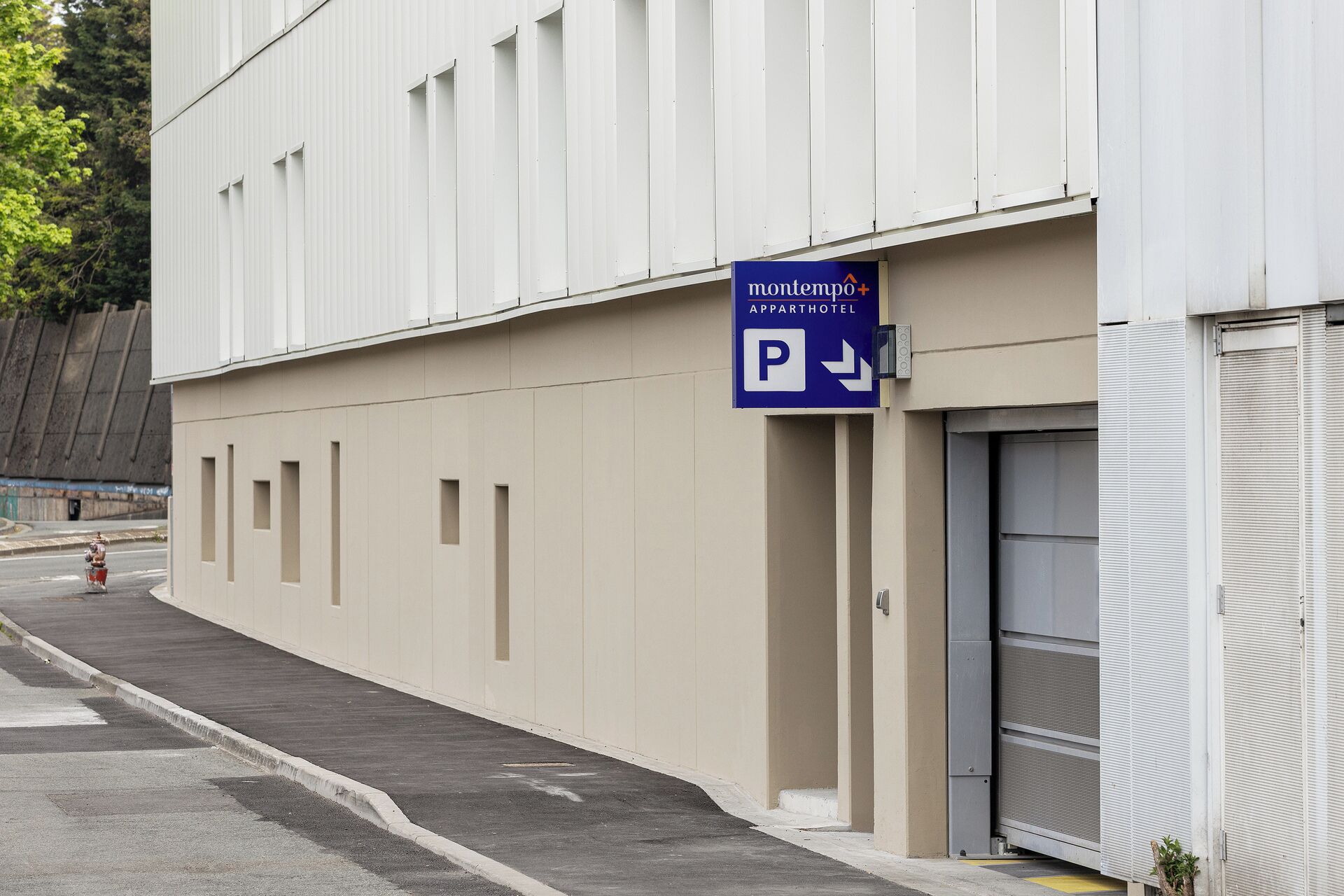 Un immeuble avec un panneau indiquant un parking pour le Montempo+ Apparthotel.