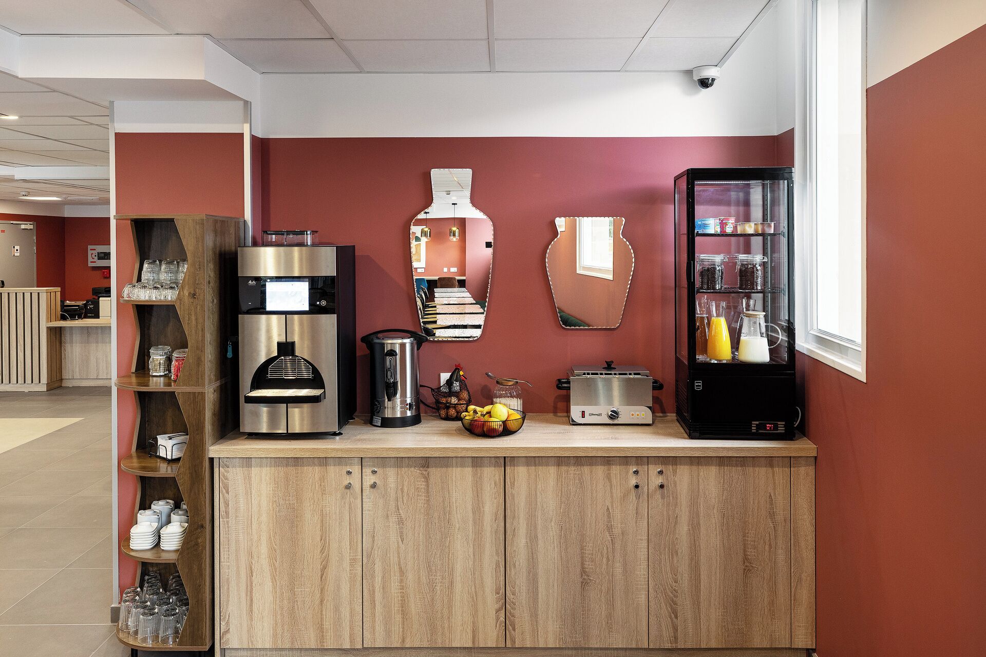 A kitchenette with a coffee machine, toaster, and refrigerator.
