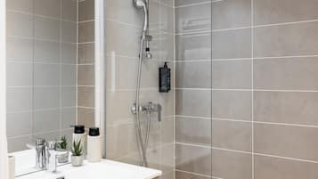 Een moderne badkamer met een douchecabine van glas, een witte wastafel met een houten kastje en een spiegel.