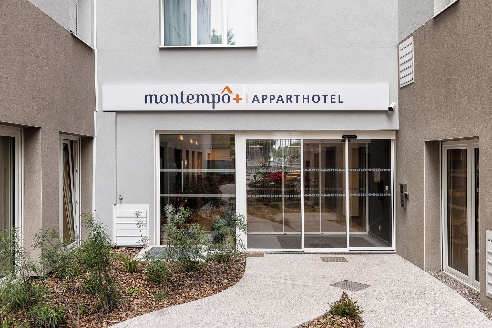 Un moderno edificio de apartamentos con un cartel que dice 'montempo | APPARTHOTEL'.