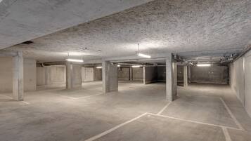 A spacious underground parking area with concrete pillars and marked parking spaces.