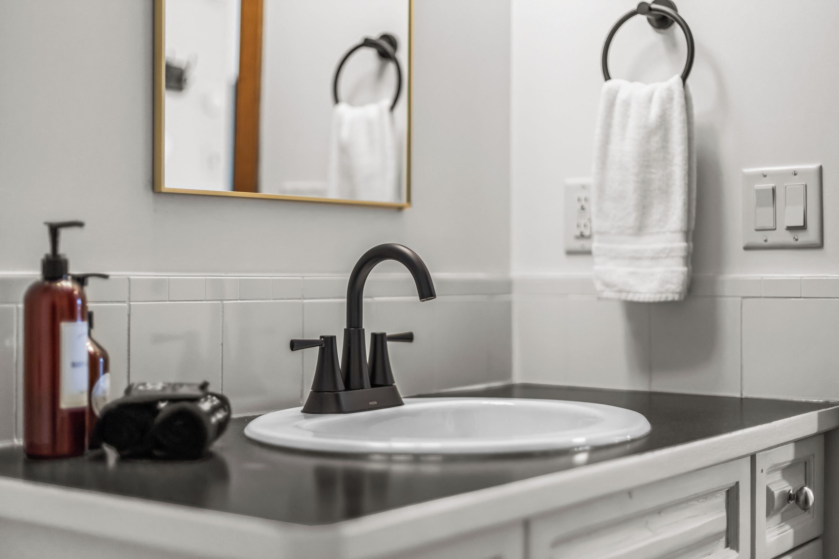A bathroom with a modern sink, faucet, and towel rack.