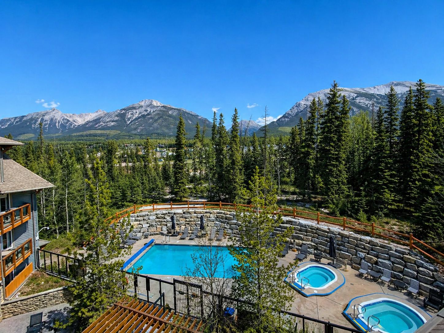 A resort with a pool, lounge chairs, and a mountain backdrop.