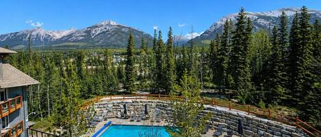 A resort with a pool, lounge chairs, and a mountain backdrop.