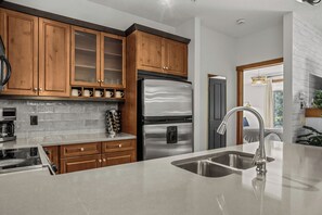 Eine moderne Küche mit Holzschränken, einem Edelstahlkühlschrank und einem eingebauten Ofen.