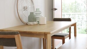 A wooden dining table with chairs, a wall clock, and decorative vases.