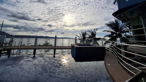 Blick auf das Wasser mit blauem Himmel, einer Anlegestelle und einem Gebäude mit einem Balkon.