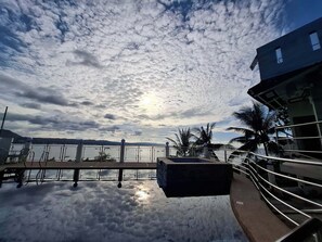 Vista sull'acqua con cielo sereno, un molo e un edificio con un balcone.