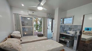 Ein Schlafzimmer mit zwei Betten, ein Badezimmer mit Spiegel und eine kleine Küchenzeile.