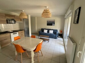 Une cuisine moderne avec une table et des chaises, un canapé bleu et un luminaire suspendu.