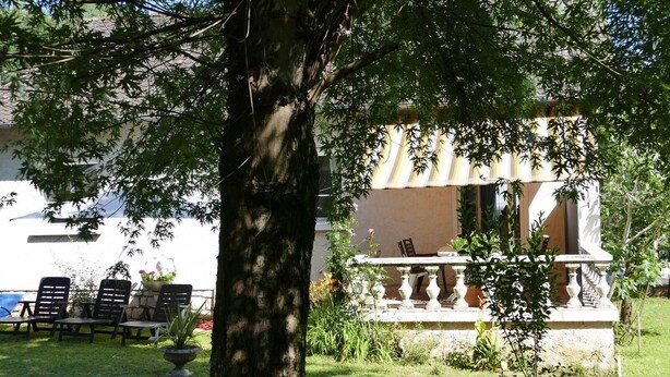 A tree-lined outdoor seating area with a stone balustrade, a white building with a beige facade, and a clear sky. - Gîte -le-7 à Brive la Gaillarde - Quiet house, garden and parking space (Brive-la-Gaillarde)