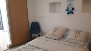 A bedroom with a bed, two pillows, a blue chair, and a dreamcatcher on the wall. - Small villa sleeps 6, near the calanques.  Ideal for hiking and climbing (Marseille)