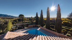 Ein Schwimmbecken mit einer Pergola, umgeben von Zypressen und Blick auf die Landschaft.