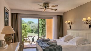 Ein Hotelzimmer mit Bett, Tisch, Stuhl, Deckenventilator und Blick ins Freie.