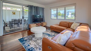 Ein Wohnzimmer mit einer Couch, einem Fernseher und einem Essbereich mit Stühlen und einem Tisch.