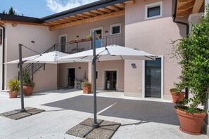 A building with a covered outdoor area, potted plants, and a staircase. - 'Camera Olio' with Shared Garden, Wi-Fi and Air Conditioning (Negrar di Valpolicella)