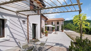 Un patio con pérgola, mobiliario exterior y plantas en macetas.