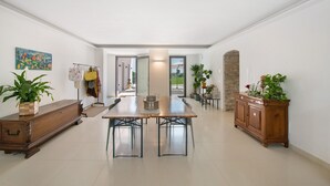 Una habitación amplia con una mesa de madera grande, un armario y una planta en maceta.