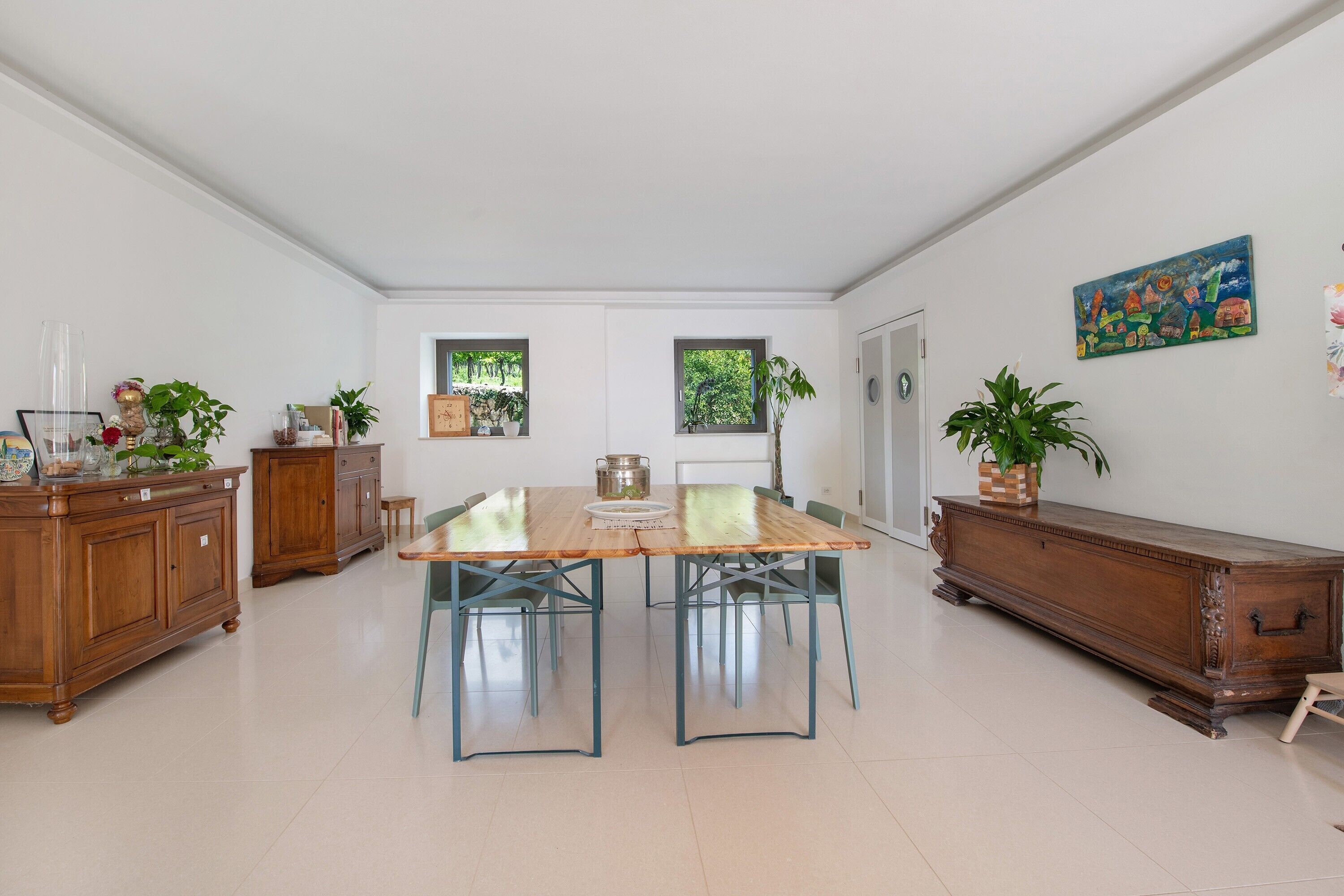 A spacious dining area with a long wooden table, chairs, and a cabinet.
