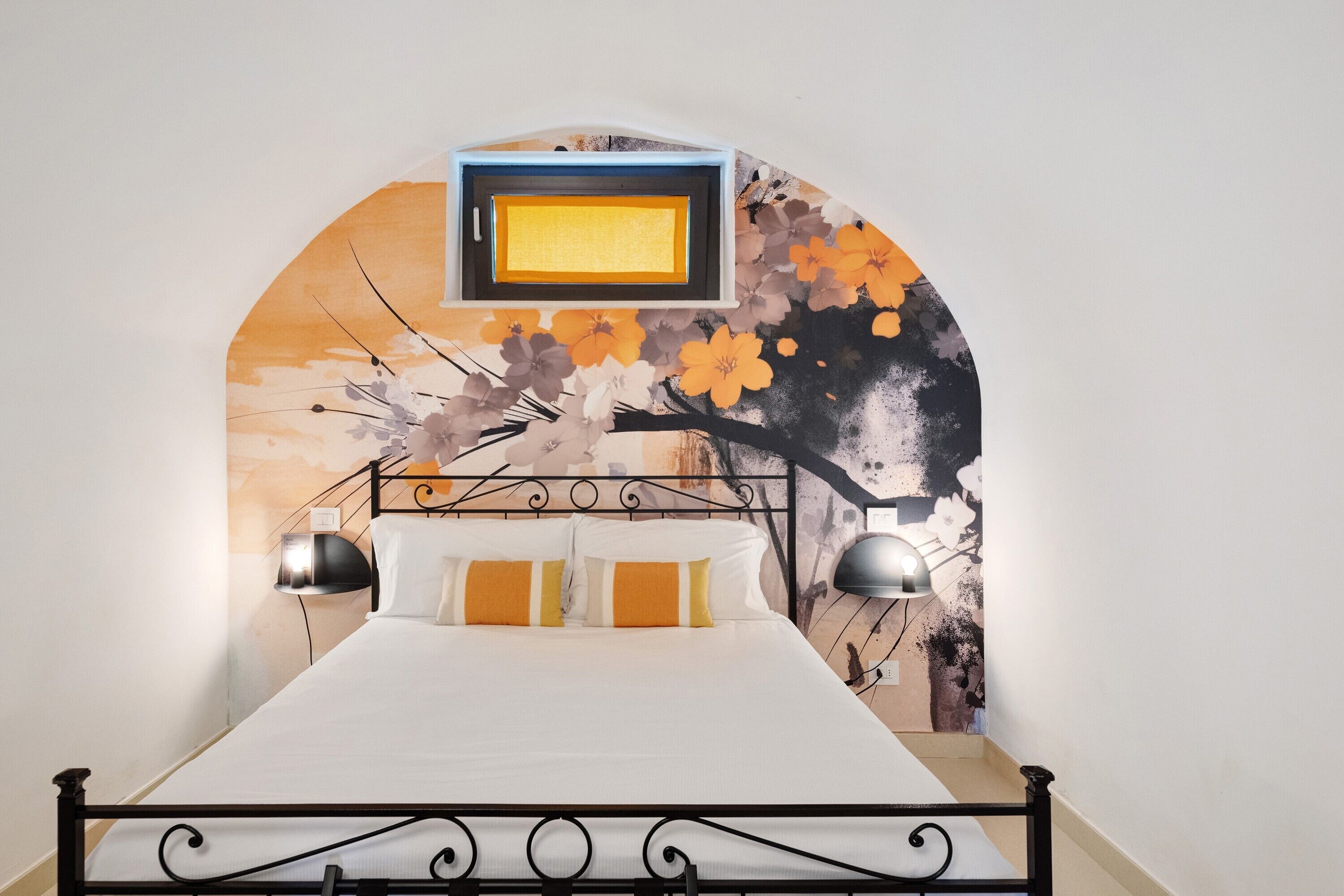 Een bed met een witte matras, een zwart metalen frame en twee bedlampjes.