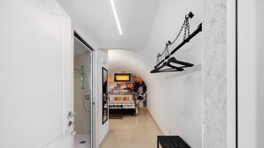 A hallway with a bed, a TV, and a wall-mounted rack.