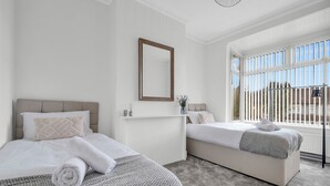 Quarto de hotel com duas camas, uma janela grande e vista para o exterior.