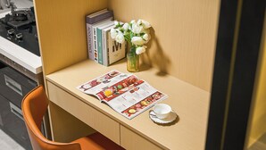 A small wooden desk with a menu, a vase with white flowers, and a few books.