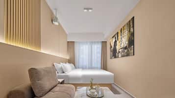 Une chambre d’hôtel comprenant un lit, un canapé, une petite table avec un plateau, et un projecteur fixé au mur.