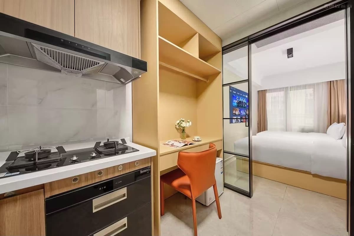 Una habitación de hotel moderna con kitchenette, un escritorio con silla y una cama.