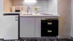 A modern kitchen with white cabinets, a stainless steel range hood, a built-in dishwasher, and a compact refrigerator.