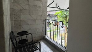 A balcony with a tiled floor, a metal chair, and a white awning. - And Living Hotel (Depok)