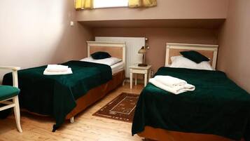 Una habitación con dos camas, una mesita y una silla.