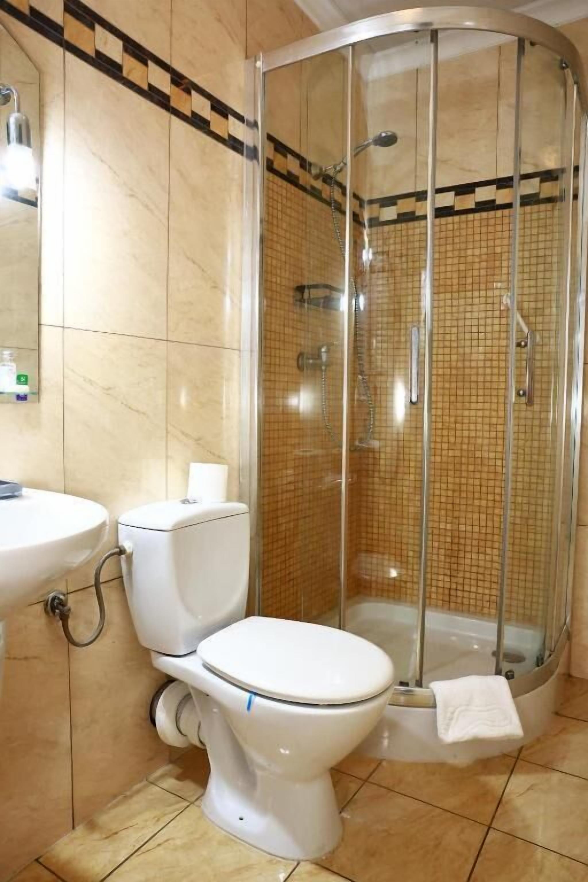A bathroom with a toilet, sink, and a glass-enclosed shower area.