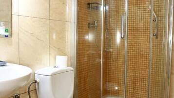 A bathroom with a toilet, sink, and a glass-enclosed shower area.