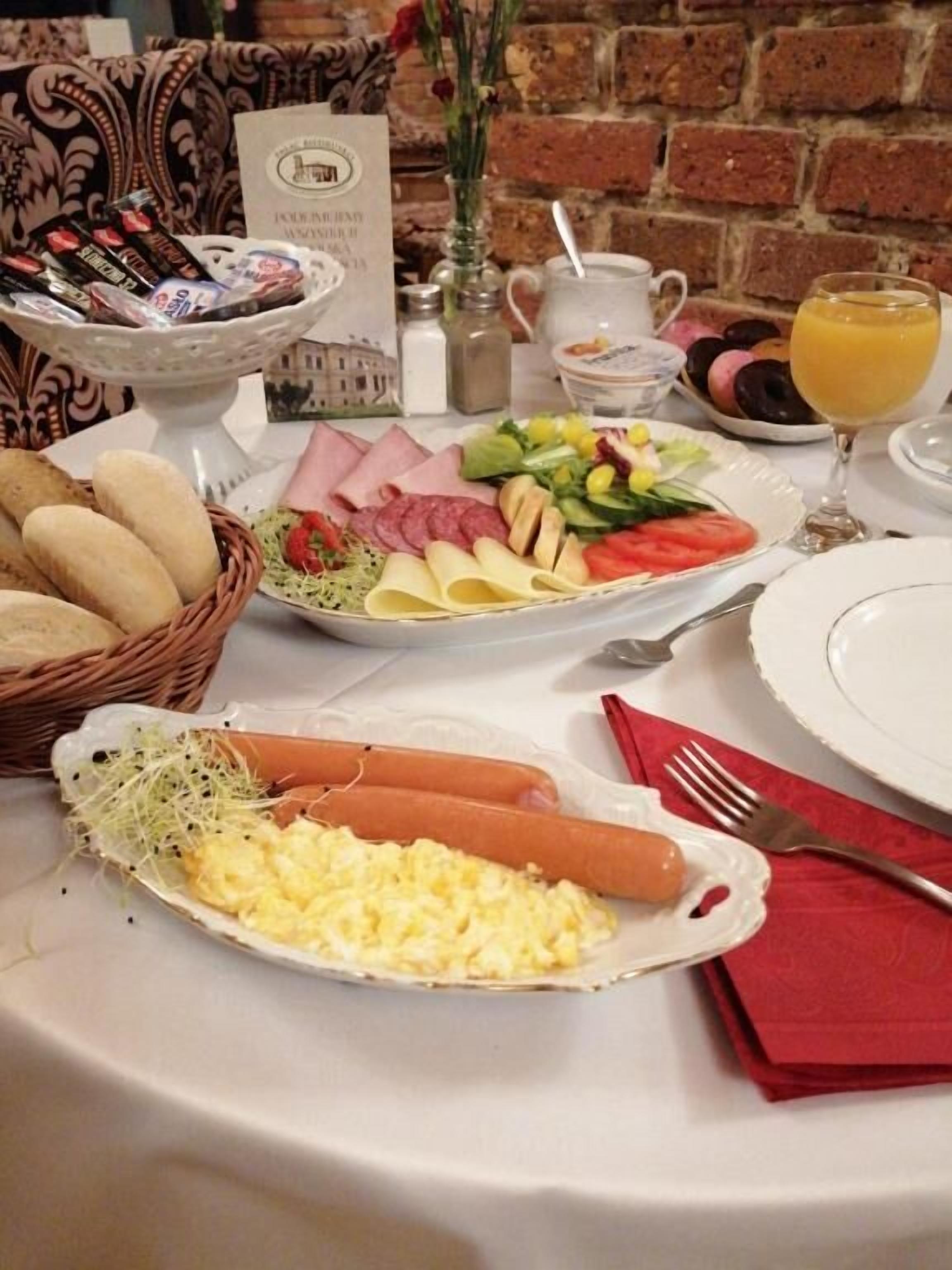 Un bufé de desayuno con diversas opciones de comida, un jarrón con flores y una pared de ladrillo al fondo.
