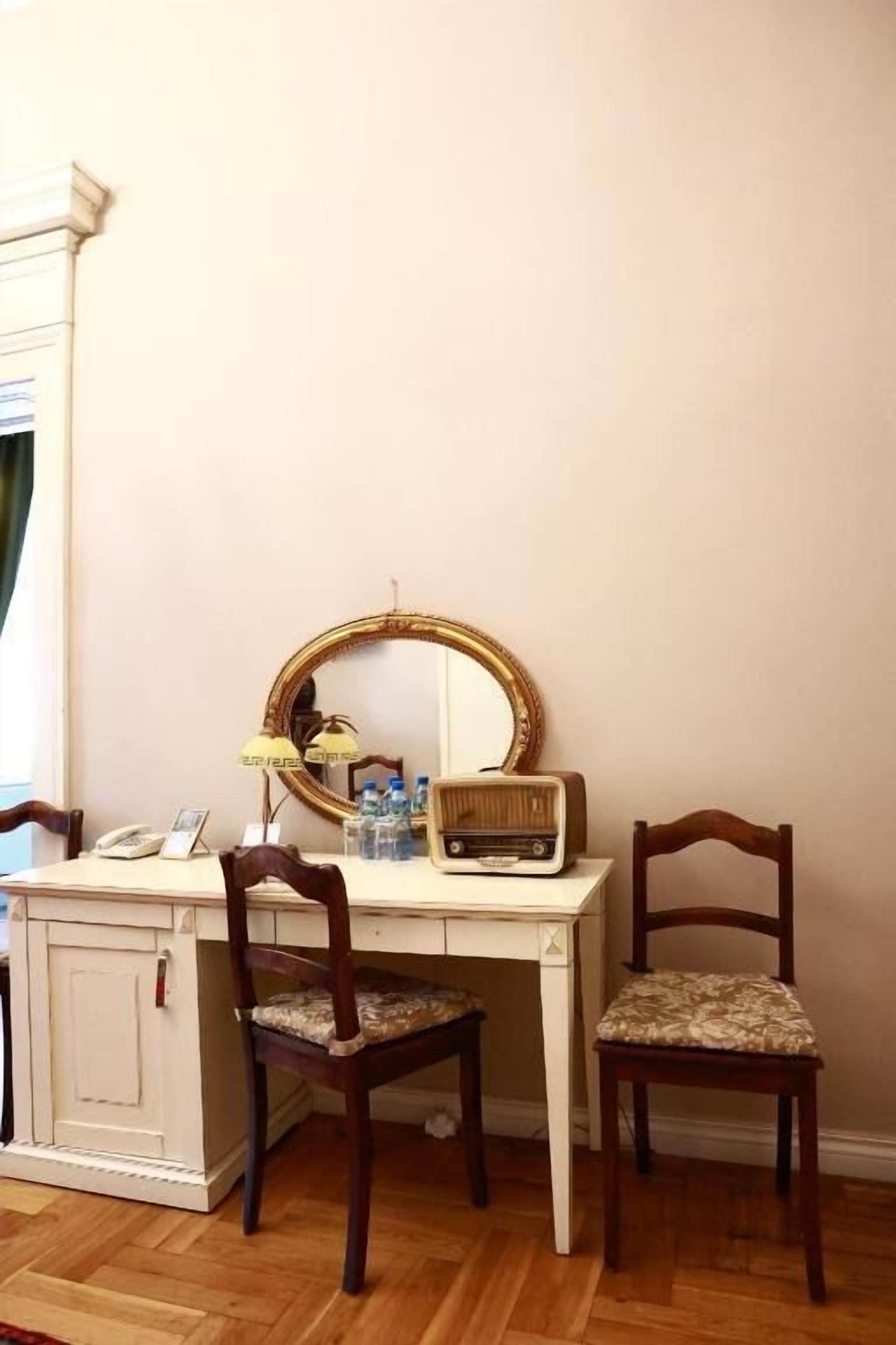 Una habitación con escritorio, dos sillas, un espejo, una lámpara y un radio.