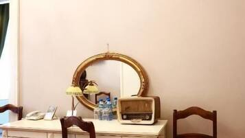 Una habitación con escritorio, dos sillas, un espejo, una lámpara y un radio.