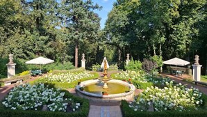 Un jardin agrémenté d’une fontaine, de coins salon et d’une statue.