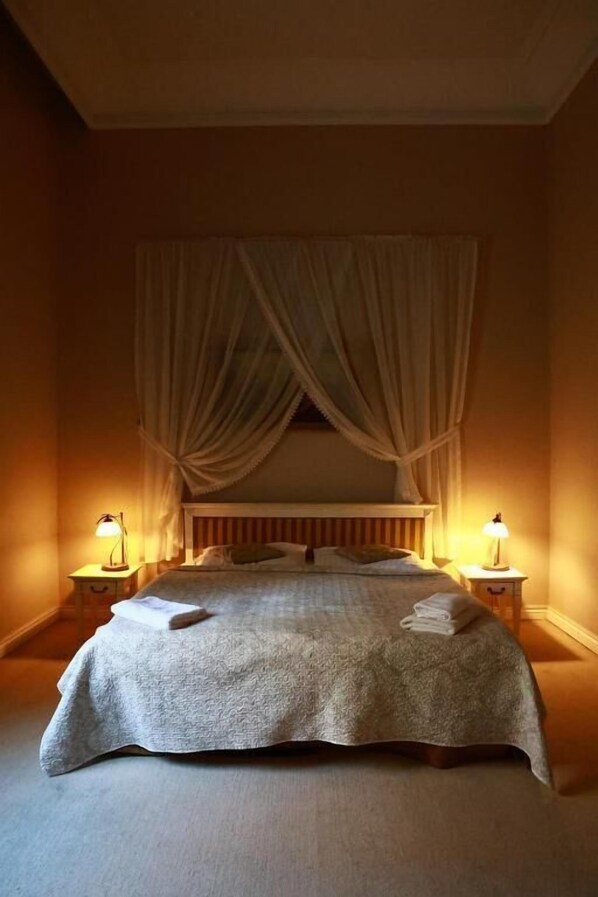 A bedroom with a bed, curtains, two bedside lamps, and a bedside table. - Pałac Biedrusko (Suchy Las)