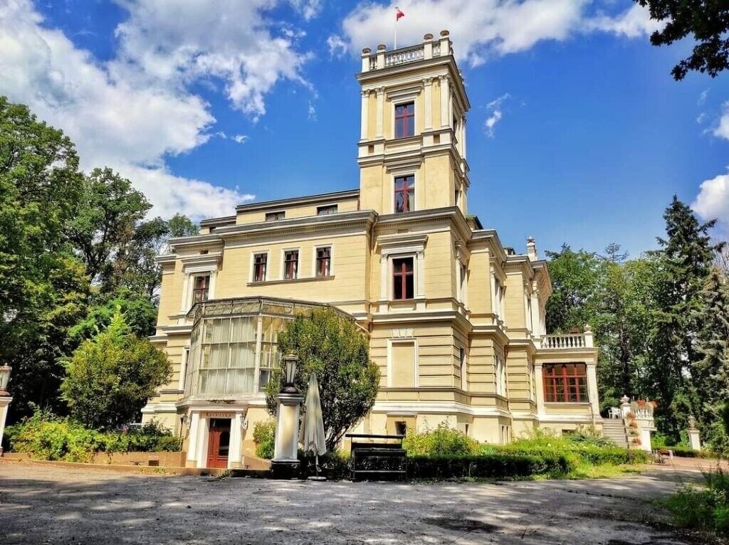 Un edificio grande e histórico con una torre destacada, fachada simétrica y una entrada central.
