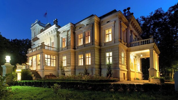 Un grand bâtiment historique doté de nombreuses fenêtres et d’un jardin bien entretenu.
