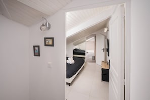 Ein Schlafzimmer mit Bett, Nachttisch, Spiegel und einer Tür zu einem anderen Raum.