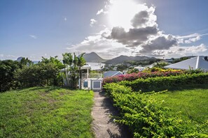 Ein Weg führt zu einem verschlossenen Eingang, mit Blick auf Berge und Häuser im Hintergrund.