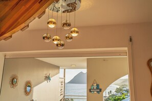 Een kamer met een houten plafond, een grote spiegel en uitzicht op zee door een raam.
