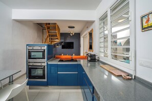 Een moderne keuken met inbouwapparatuur, een houten trap en een groot raam.