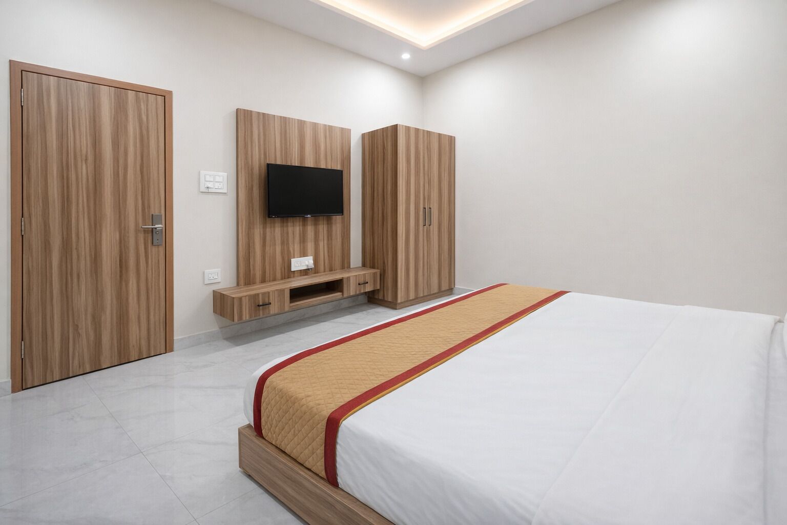 A bedroom with a bed, a TV, and wooden wardrobes.