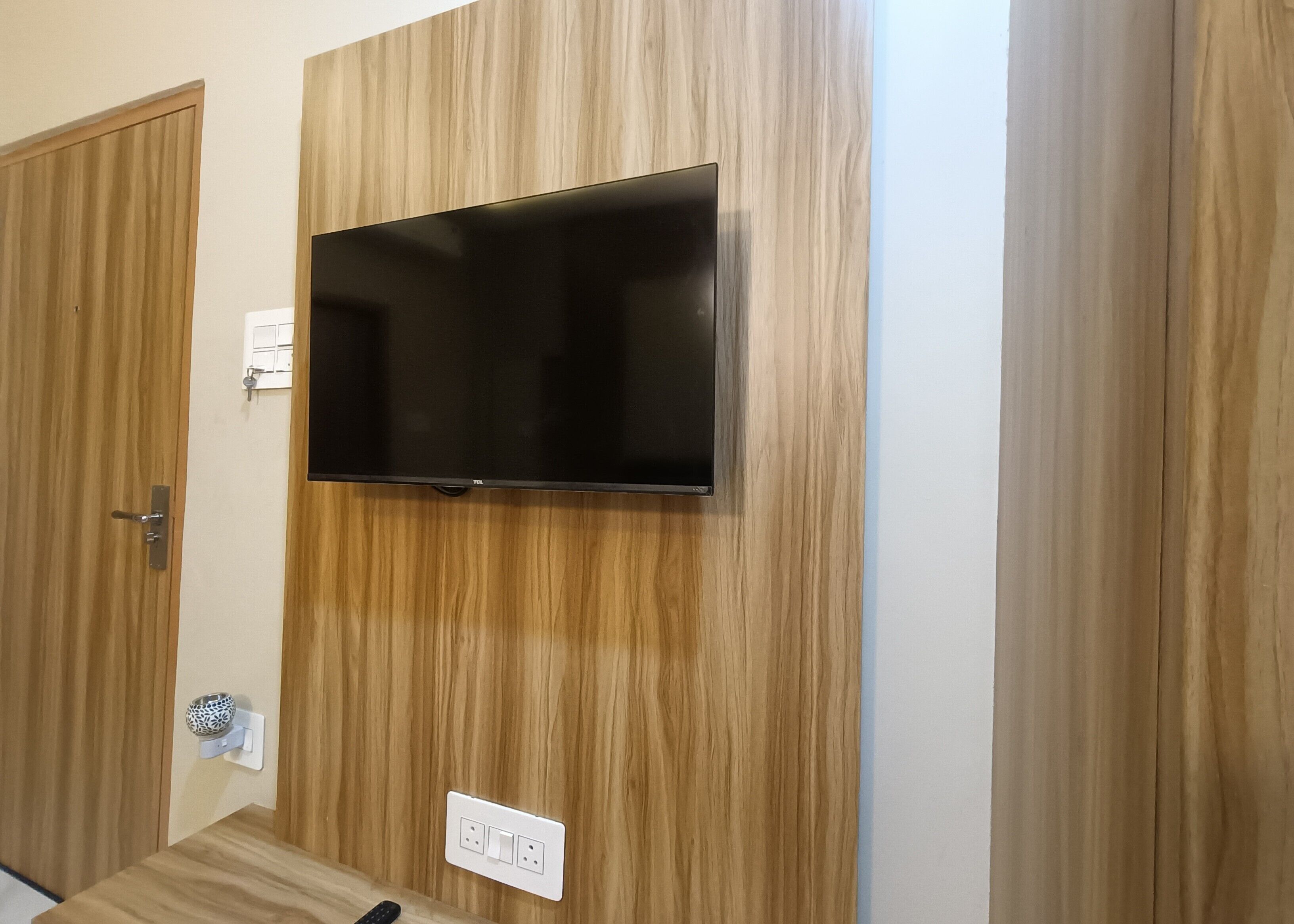 Une pièce avec un téléviseur à écran plat fixé au mur, une porte et une prise de courant.