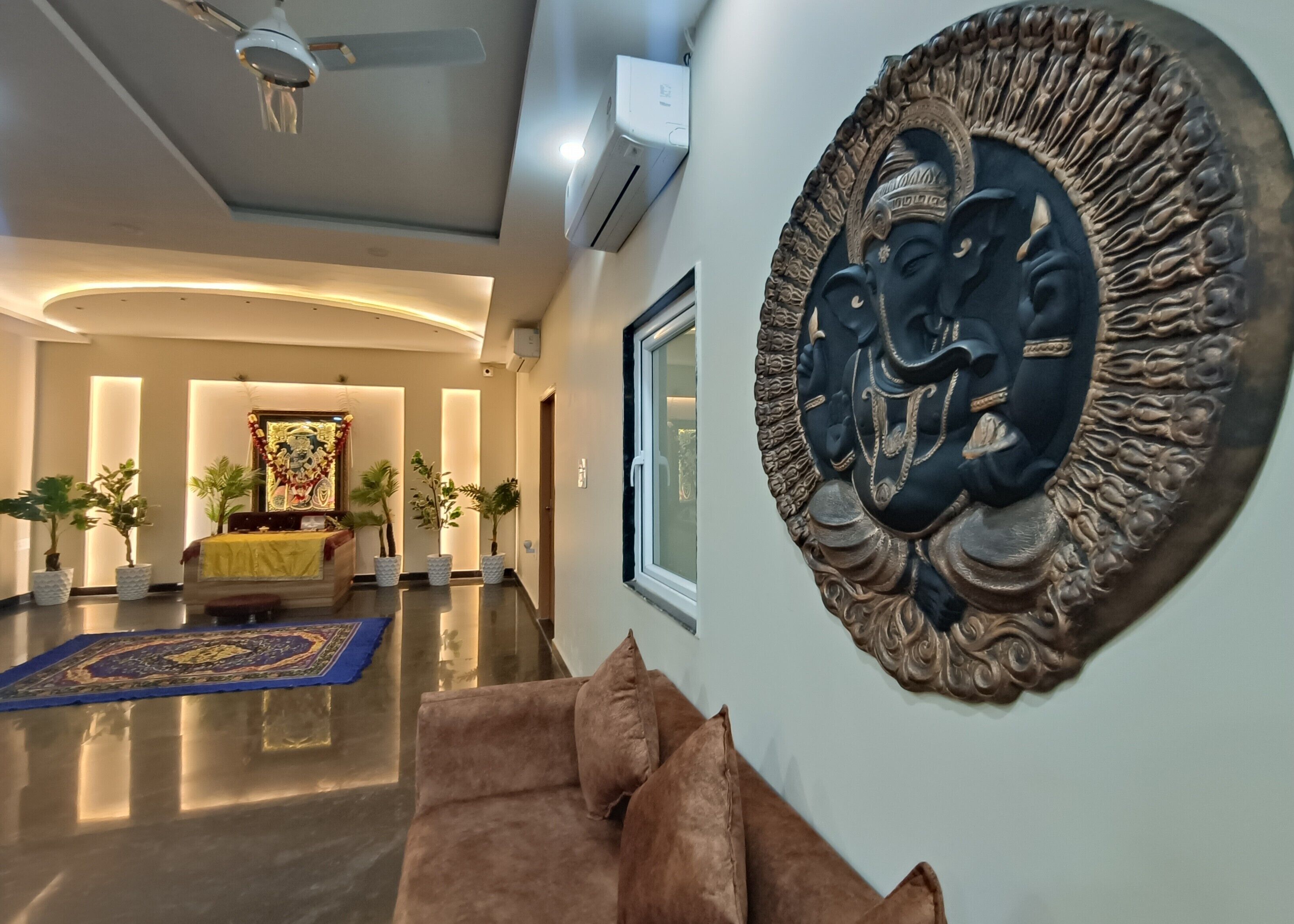 Un moderno vestíbulo de hotel con techo curvo, una gran escultura mural, un sofá con cojines y una alfombra estampada.